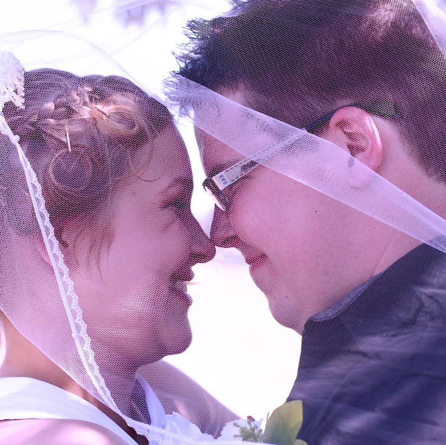 A side view of a man and a woman nuzzling their noses together on their wedding day