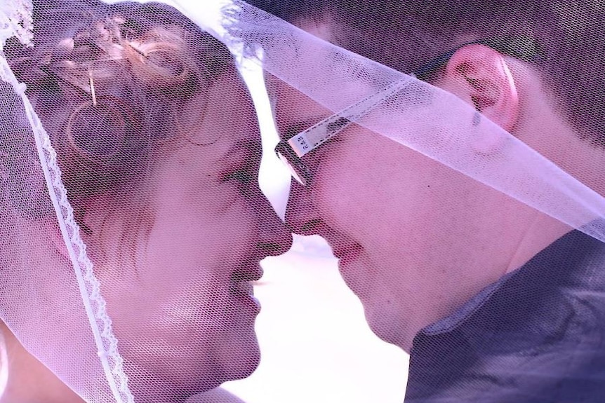 A side view of a man and a woman nuzzling their noses together on their wedding day