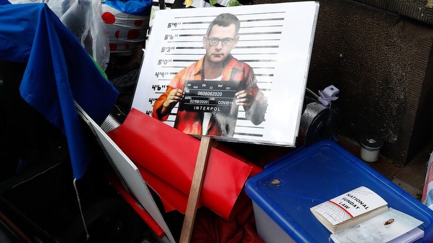 A placard showing a mock-up mug shot of Dan Andrews by the side of a protest