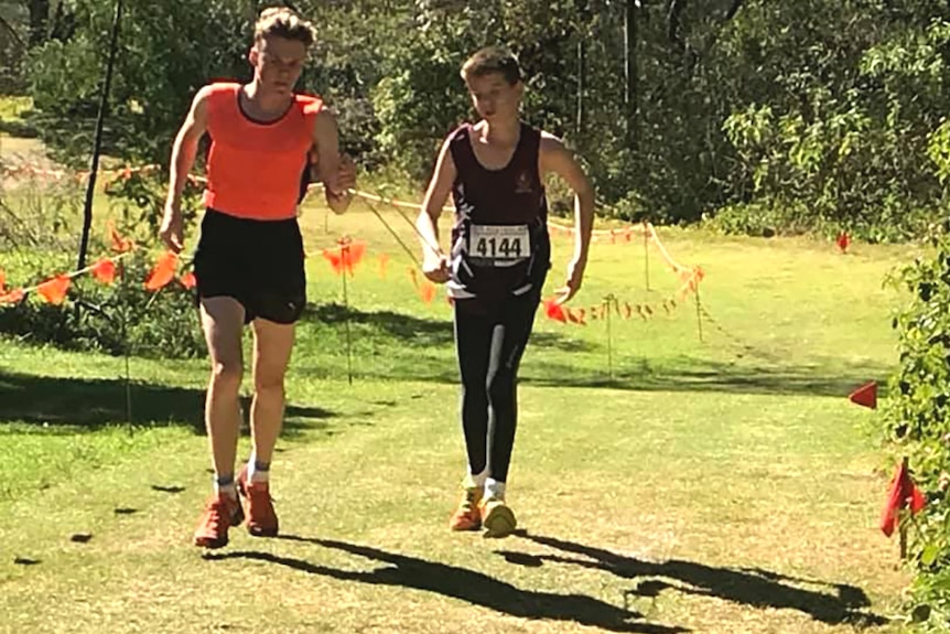 Two people running in an outdoor athletic event