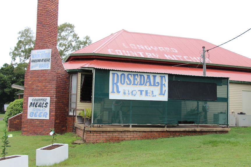 Sebuah bangunan dengan cerobong asap, tanda bertuliskan 'Rosedale Hotel'.