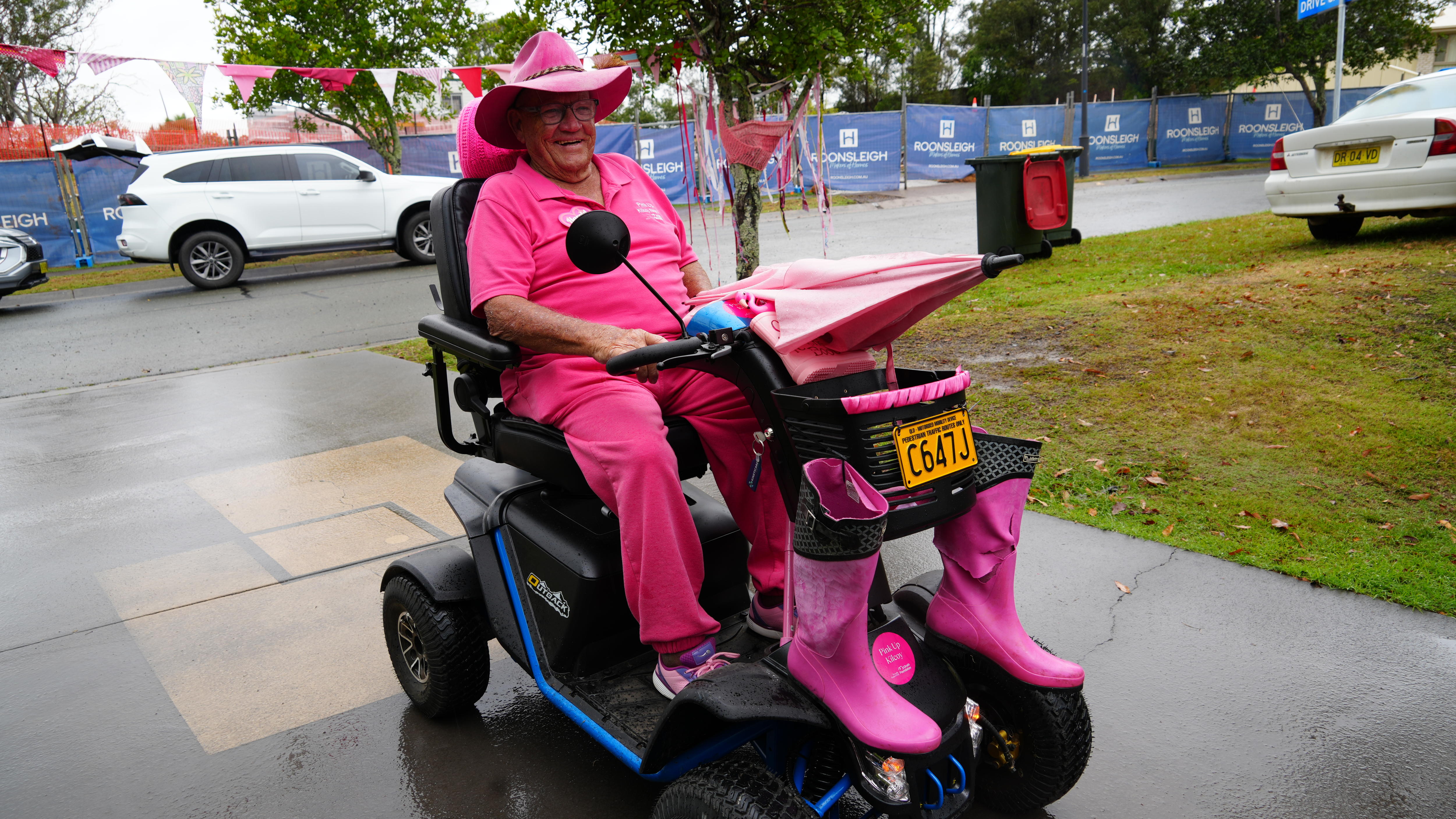 Elderly man wearing pink on pink scooter