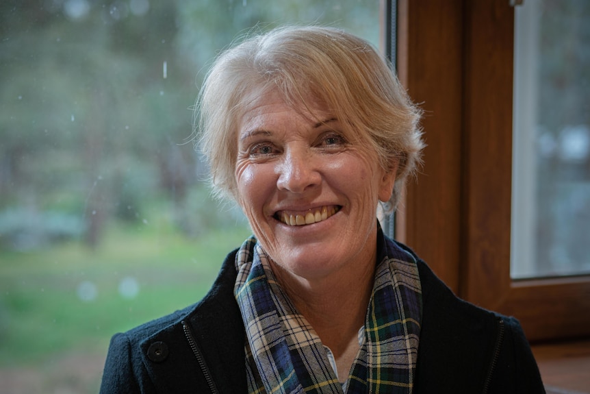 Penny Ackery wearing a coat and scarf, smiling at the camera.