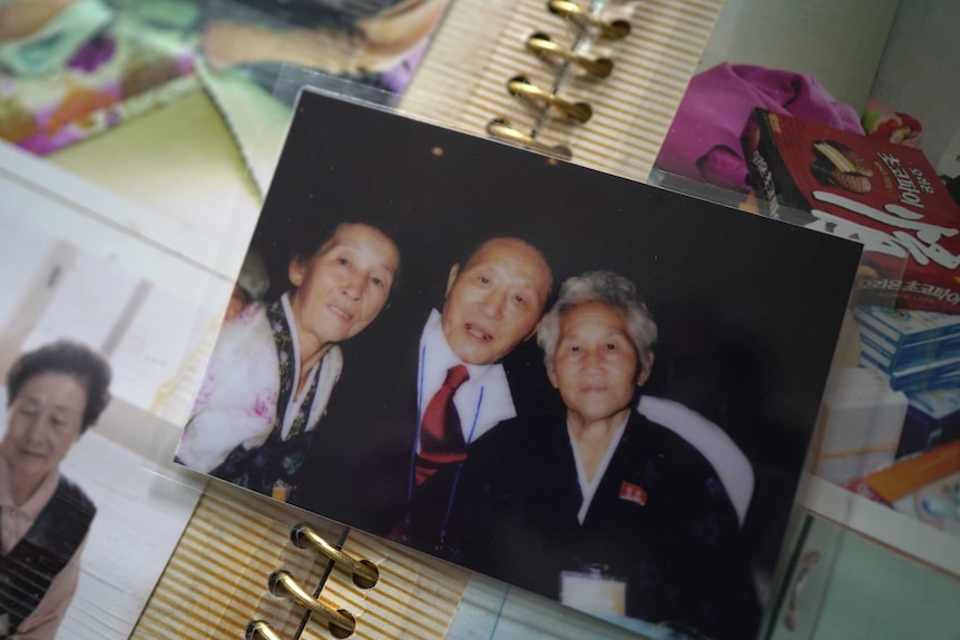 A photo shows a man sitting between two women and smiling.