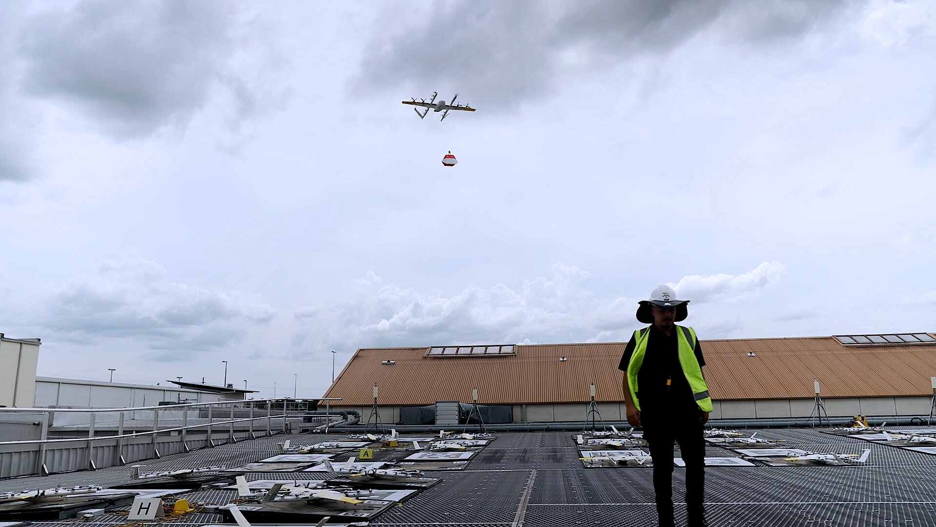 A drone flies from a rooftop carrying a bag.