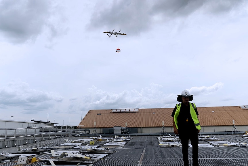 A drone flies from a rooftop carrying a bag.