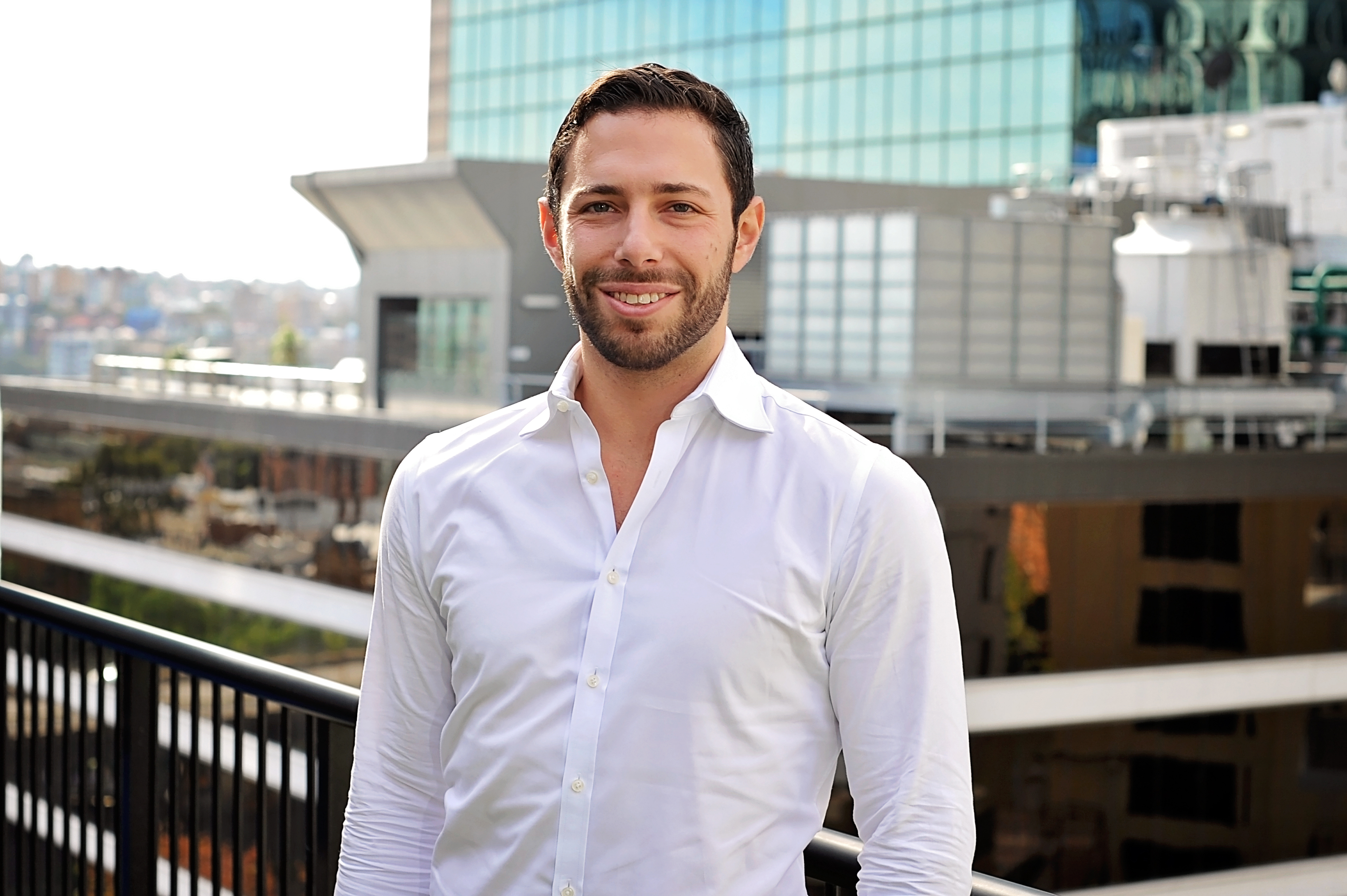 Man in white shirt standing on a building rooftop.