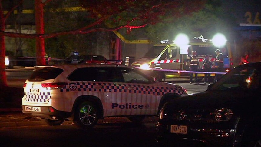 A police car and ambulance at the scene of the shooting at a fast food outlet carpark.