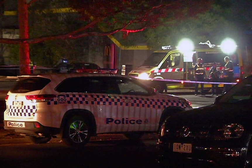 A police car and ambulance at the scene of the shooting at a fast food outlet carpark.