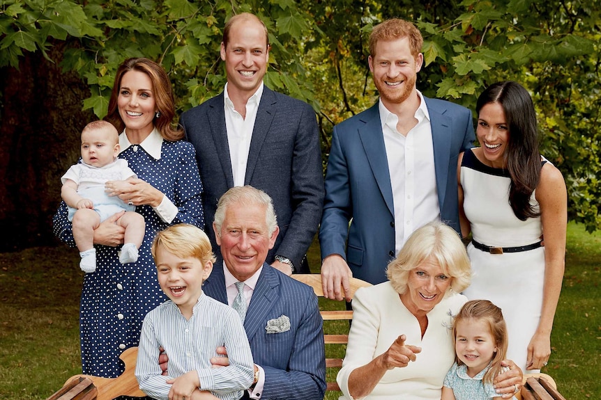 Prince Charles sits on a garden bench with grandson George on his knee, with by his wife, sons and their families, laughing