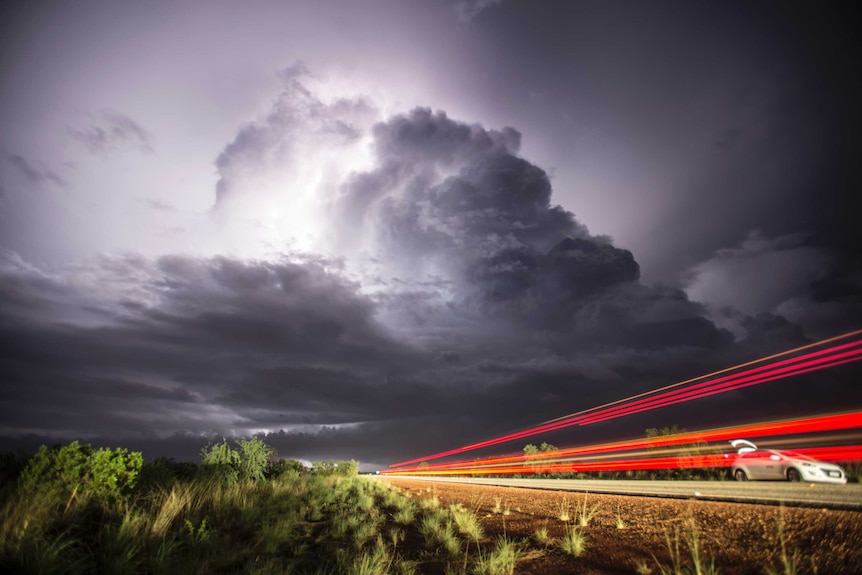 A photo of a car parked with a storm in the background