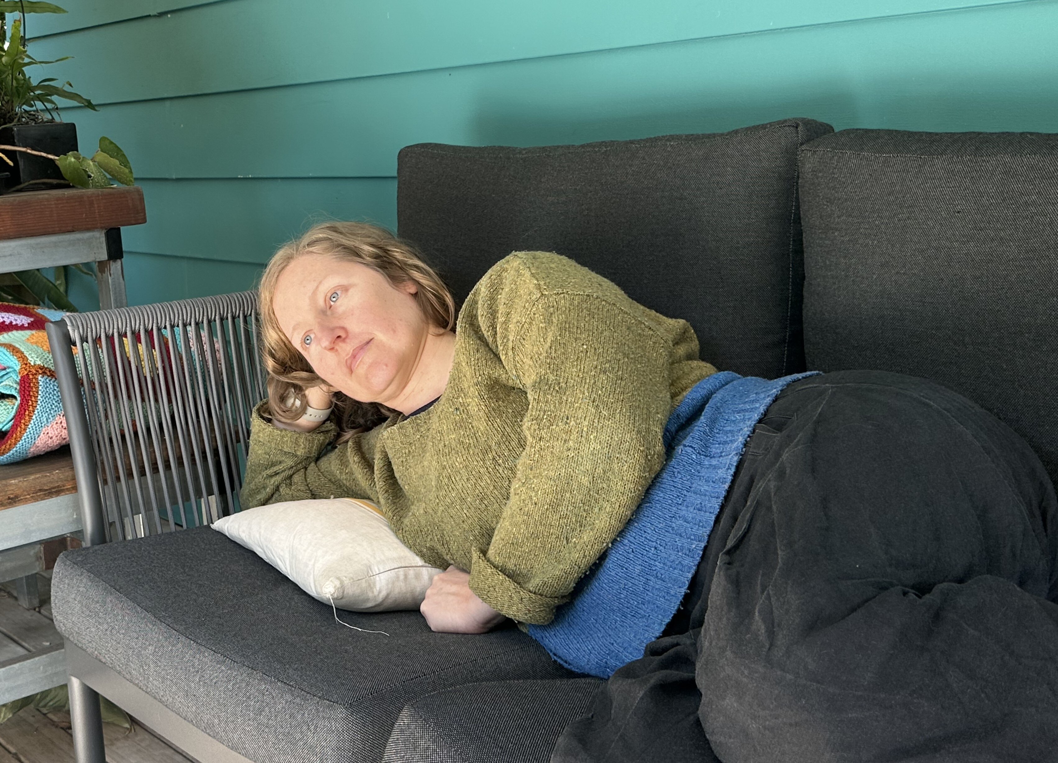A white woman with brown hair lying on an outdoor couch