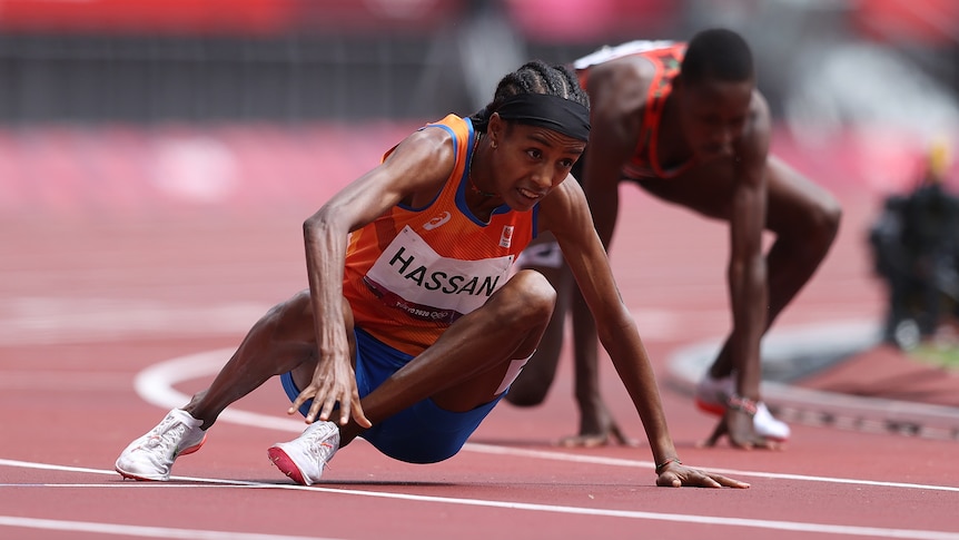 Two women getting up off the ground after tripping over during a 1,500m heat at the Olympics