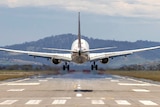 A plane prepares to touch down at an airport runway.