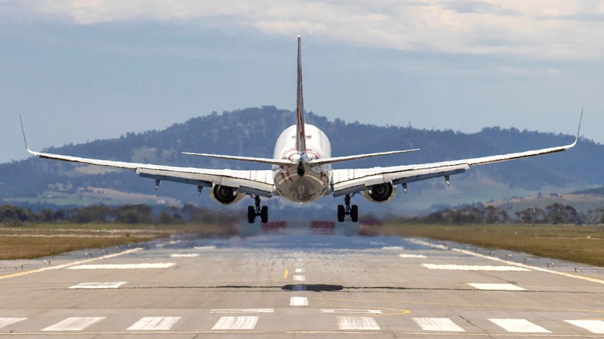 A plane prepares to touch down at an airport runway.