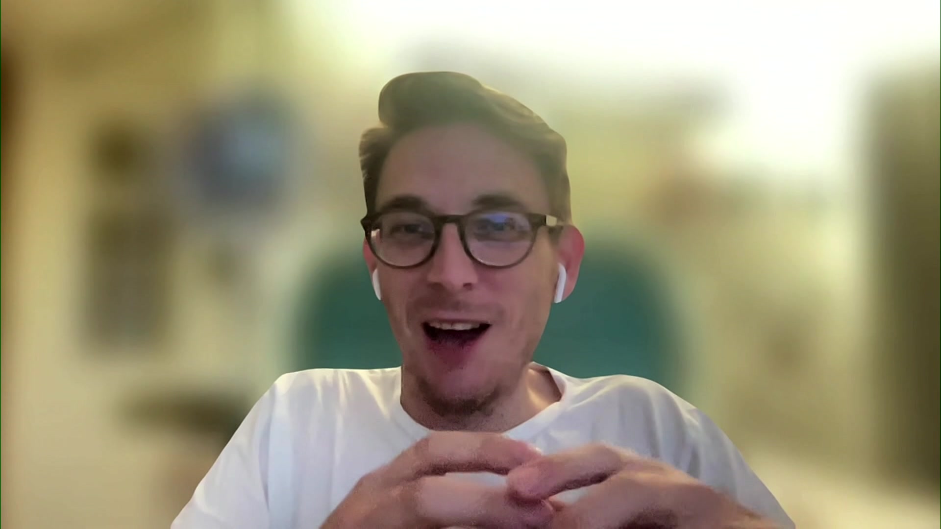 Man wearing glasses and earbuds, blurred background