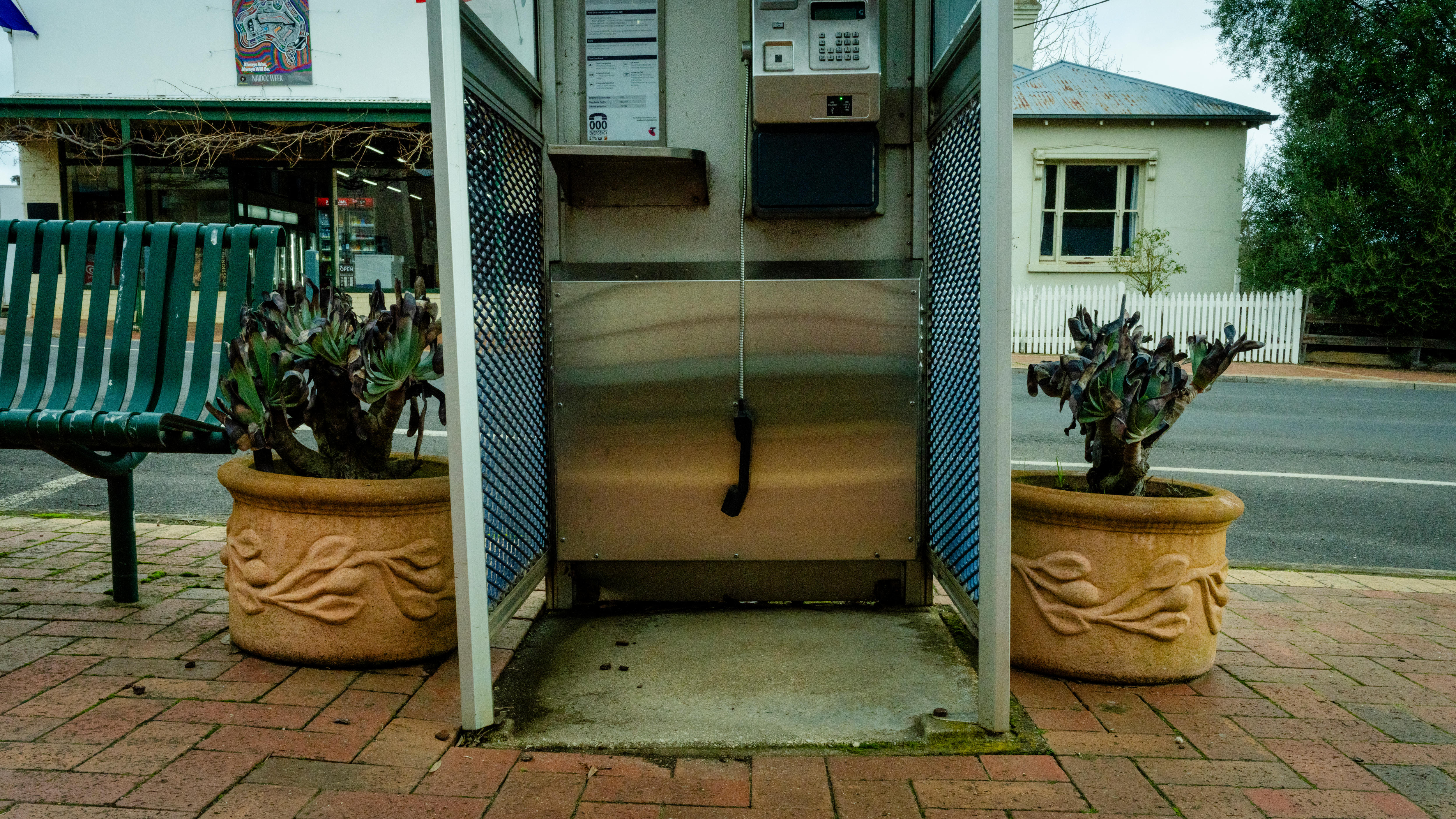 A phone booth with the handset hanging down.