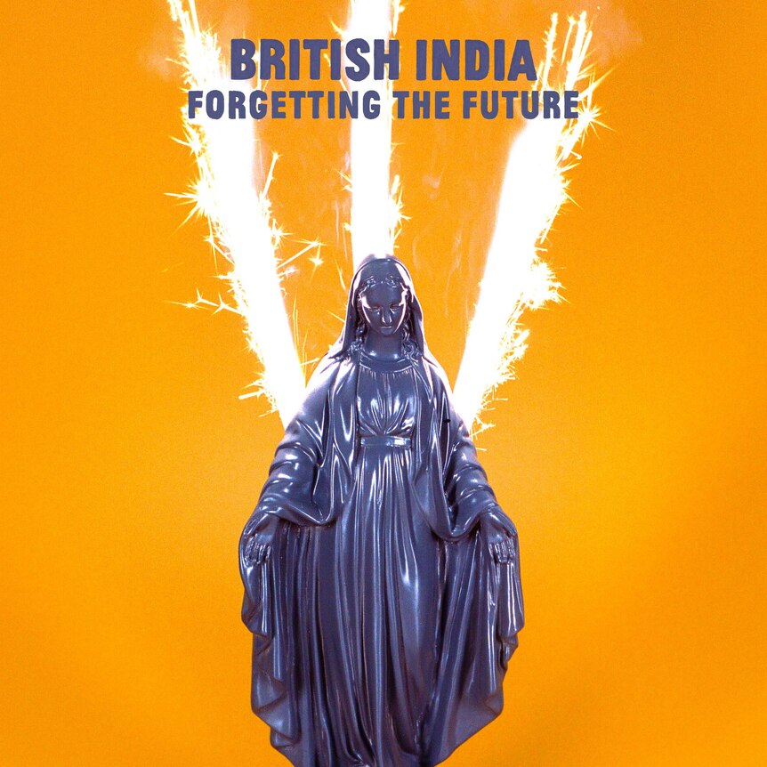 A purple statuette of the Virgin Mary with a sparkler shooting behind it on an orange background