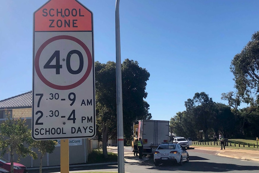 A school 40km-per-hour speed zone sign with police and the truck in the background.