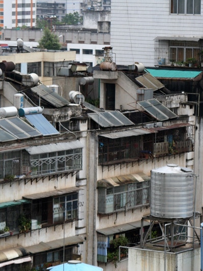 An an overcast day, you view tightly-packed medium-density apartment blocks stretching to the horizon with solar panels attached