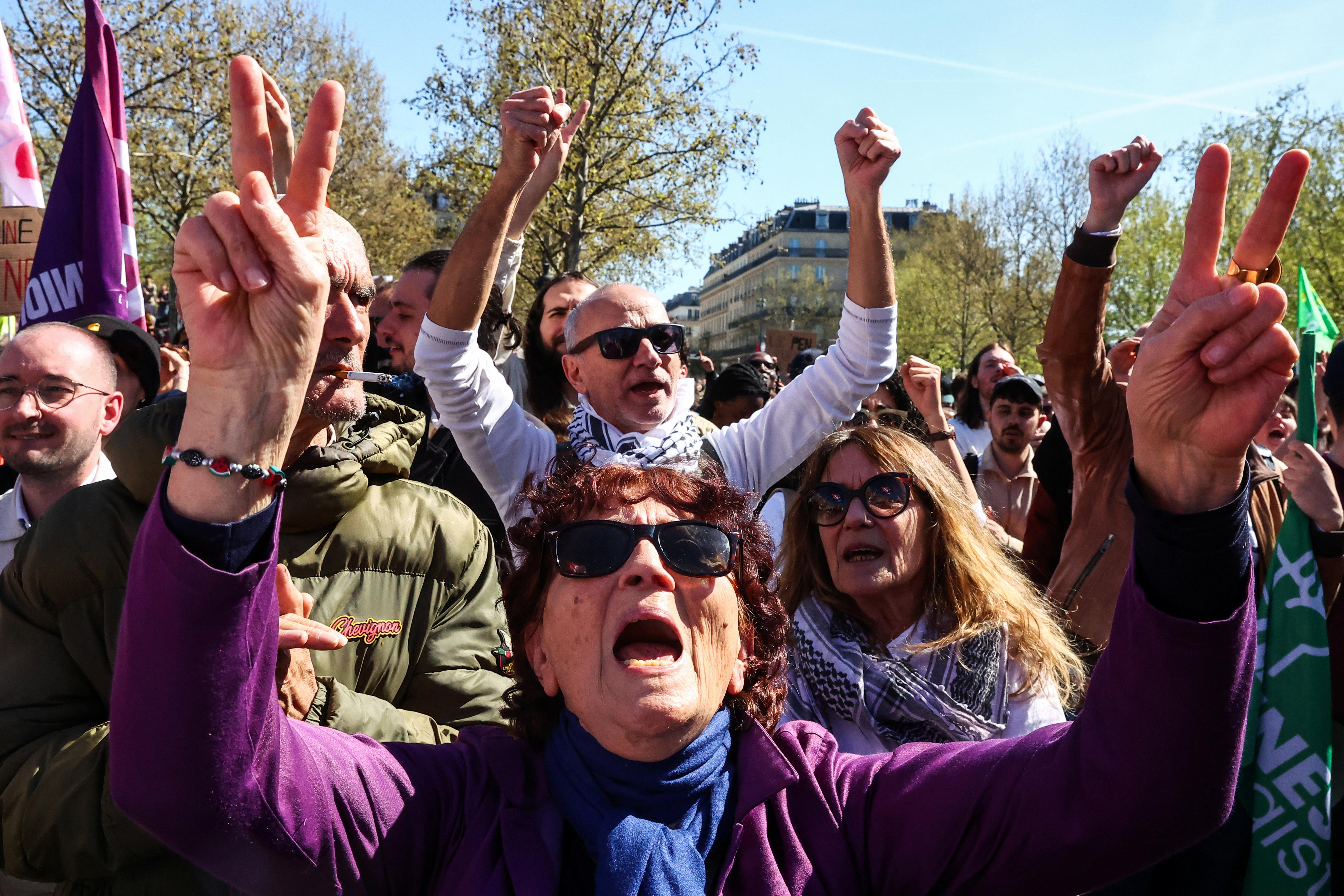 A group of protests wearing purple and raising their hands in the air.