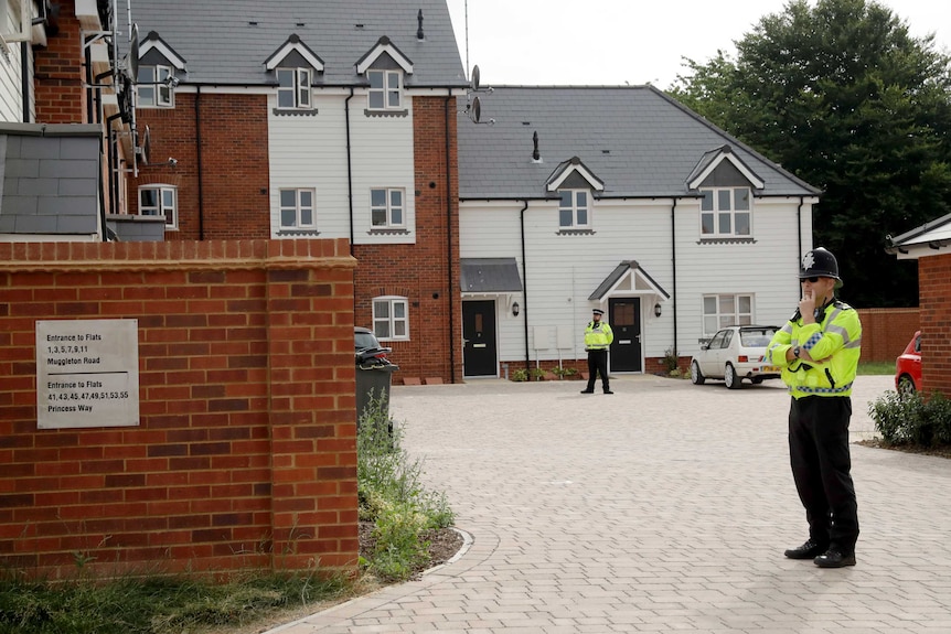 British police officers in Amesbury stand outside a residential property.