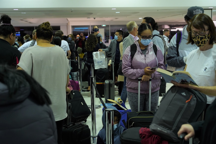 A crowd of people wearing face masks queuing at the airport.