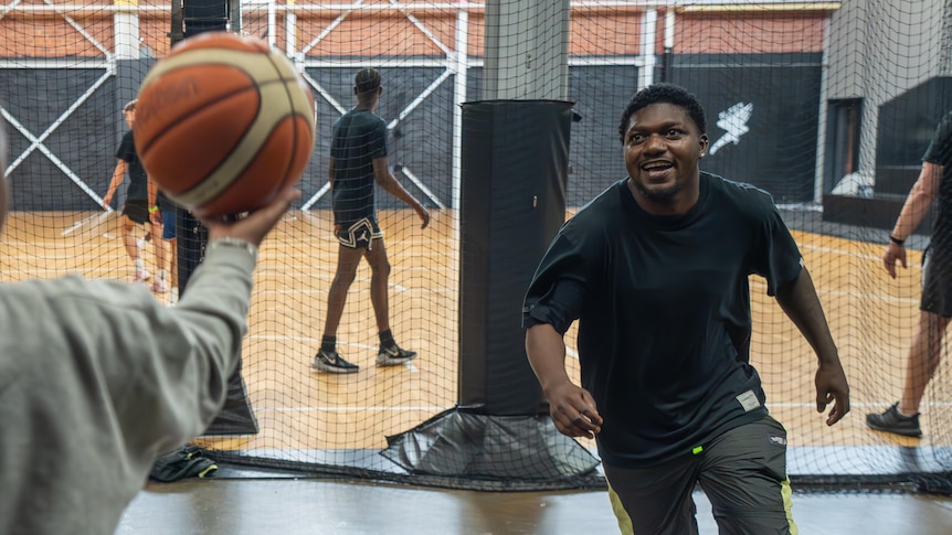 A young person lunges for a basketball.