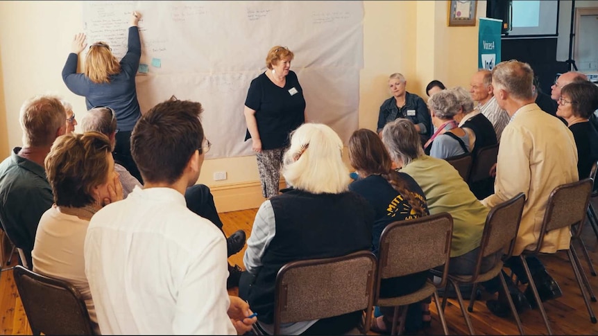 A group of community members brainstorming ideas with a sheet of butcher's paper up on the wall