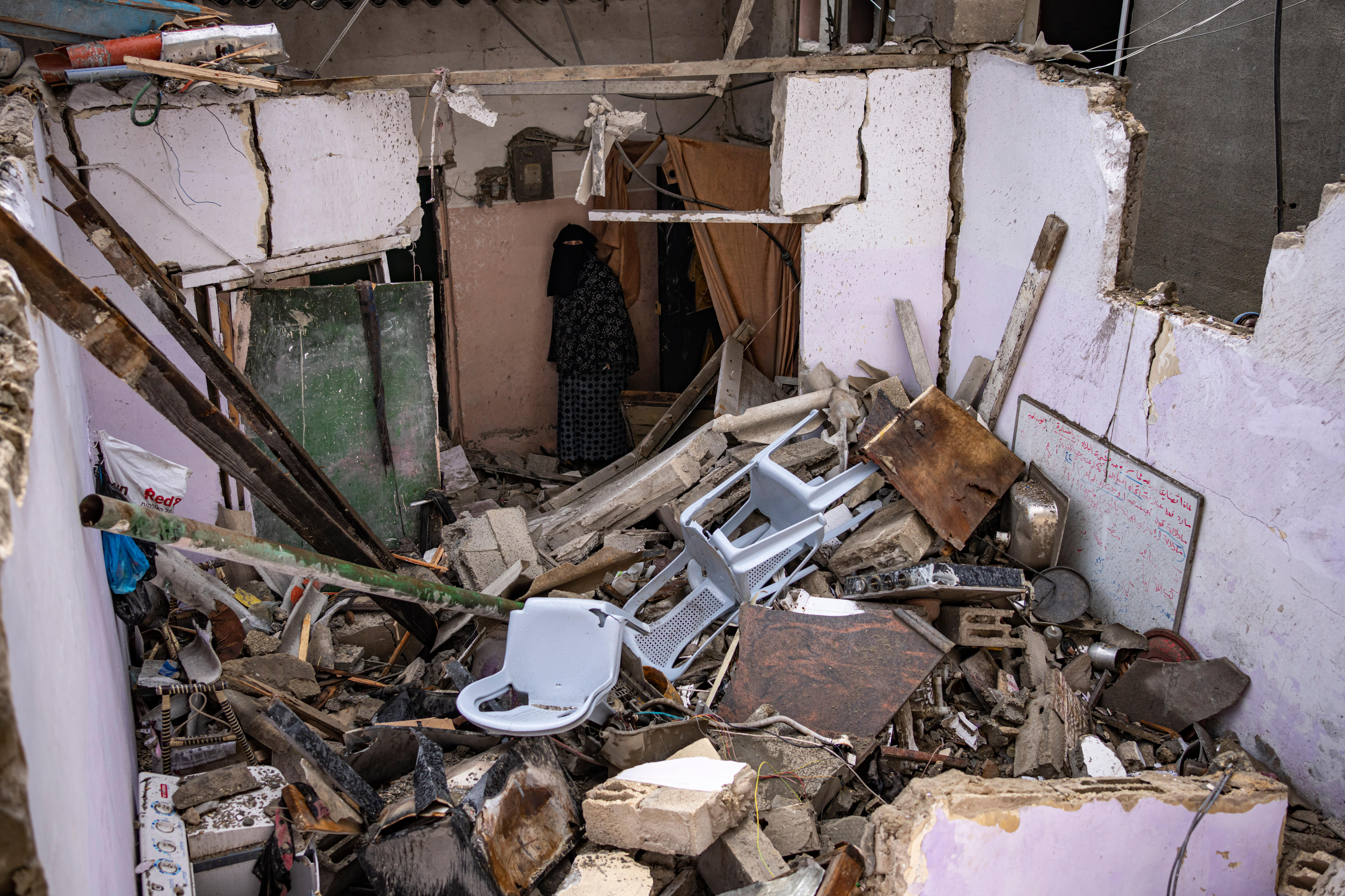 Photo of a home in debris, with chairs strewn around the wrecked site 