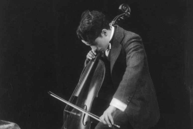 A black and white photo of Charlie Chaplin playing the cello.