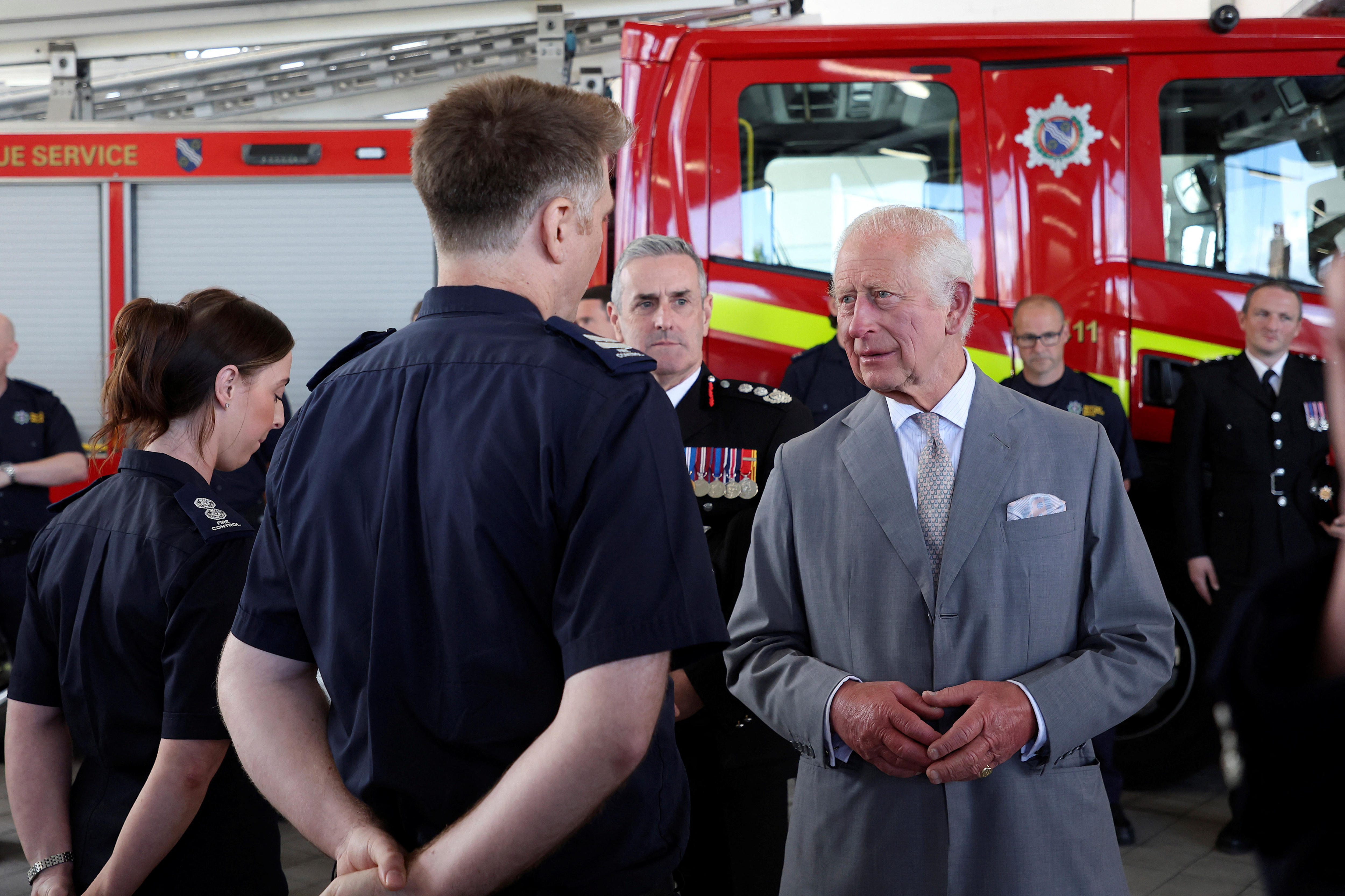 King Charles speaks to two people in ambulance uniform.