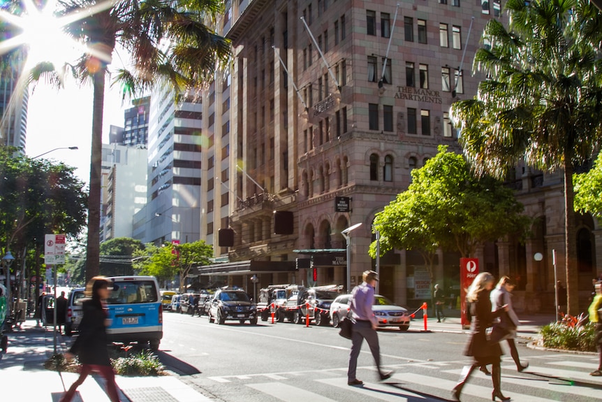 Workers rush to work in the Brisbane CBD crossing Queen Street.