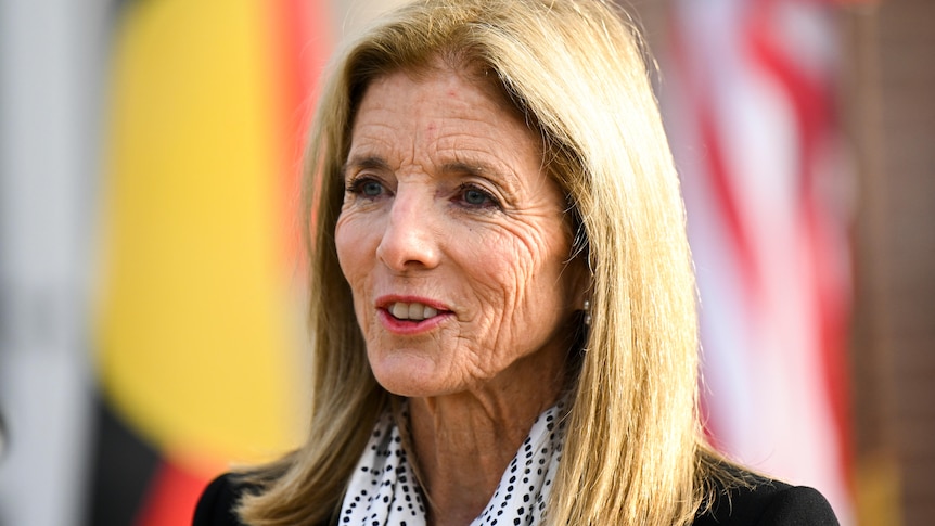 Caroline Kennedy stands in front of flags.
