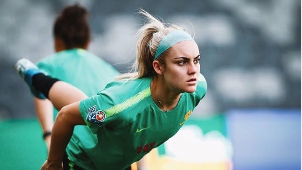 Ellie Carpenter in training gear stretching.