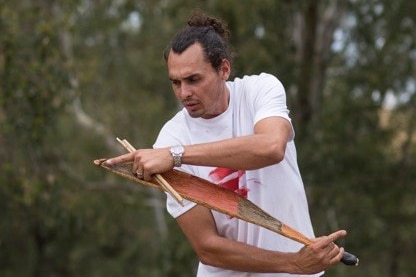 Taree Indigenous artist Andy Snelgar with one of his wooden carvings.