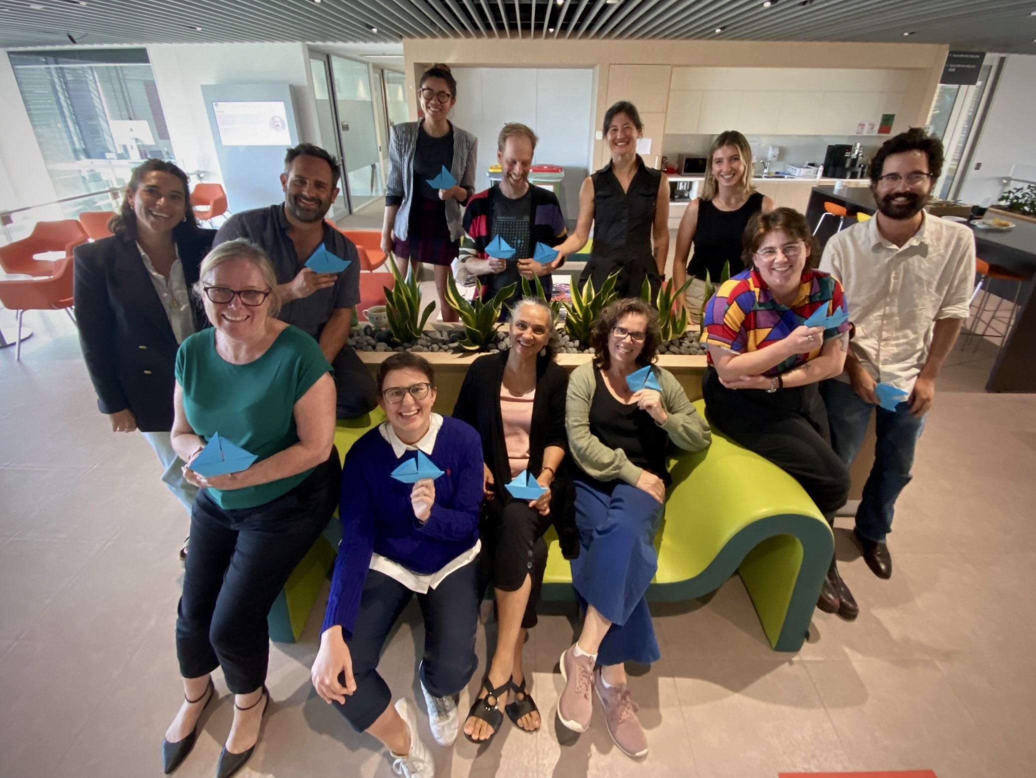 The ABC Science digital team smiles for a photo, with some staff holding paper boats.