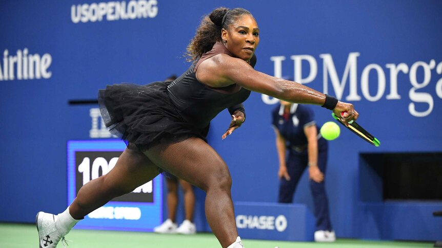 Serena Williams stretches to reach the ball with her racket, intent look of concentration. She wears a black tutu.