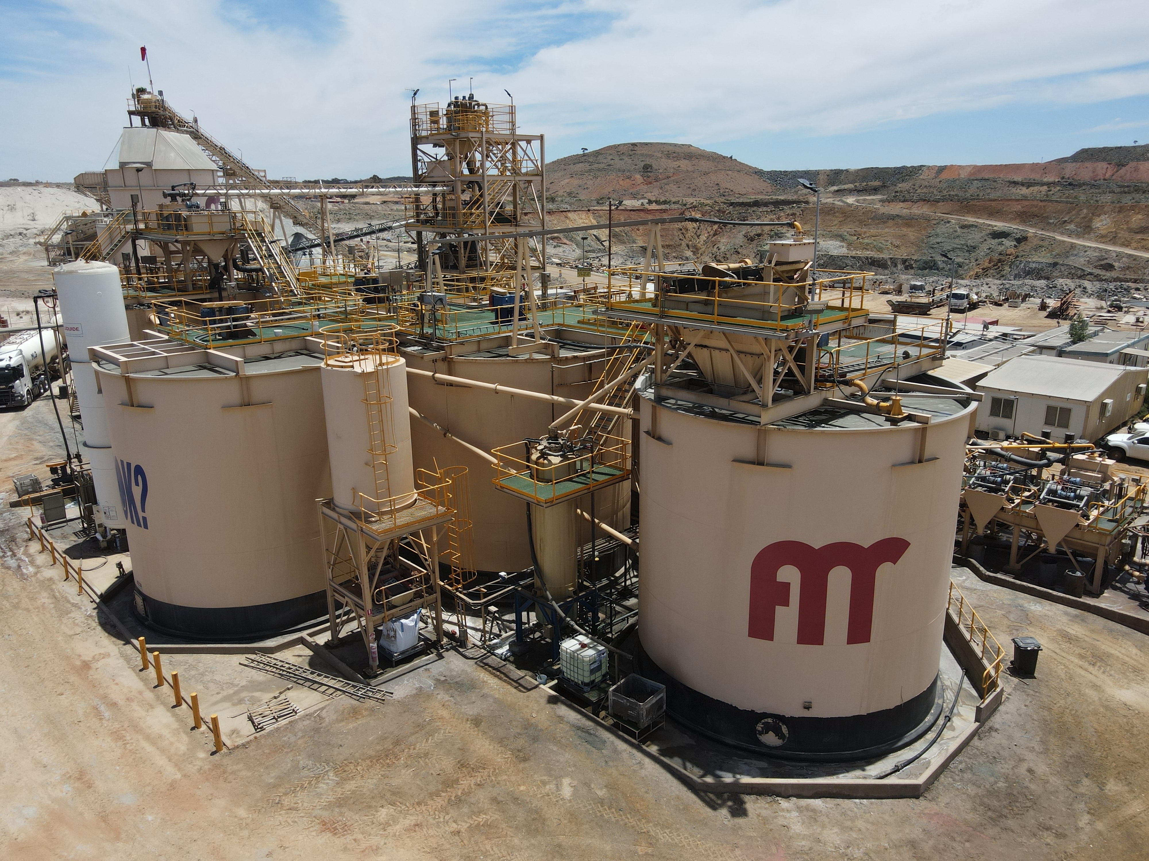 A gold processing plant with large tanks in a remote mining area.  