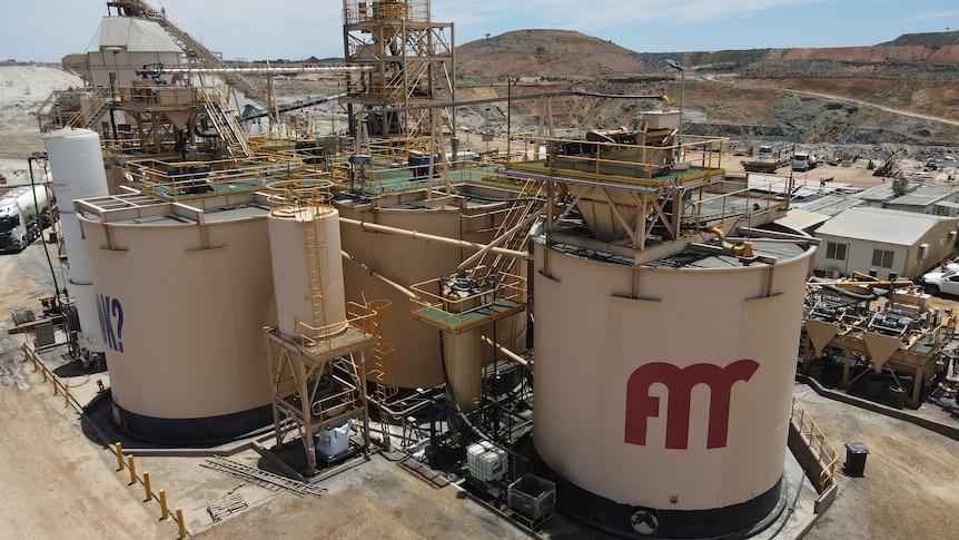 A gold processing plant with large tanks in a remote mining area.  