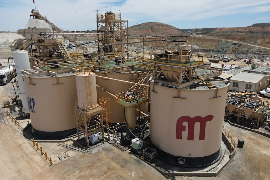 A gold processing plant with large tanks in a remote mining area.