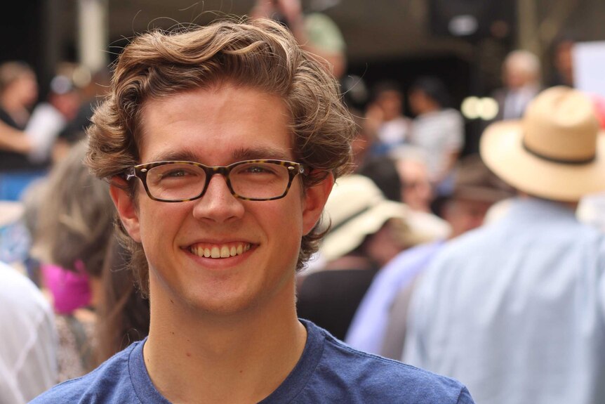 Alex Payne, an undergraduate with brown hair and glasses talks to reporters