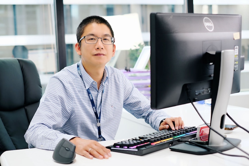 A man with glasses sits in an office.