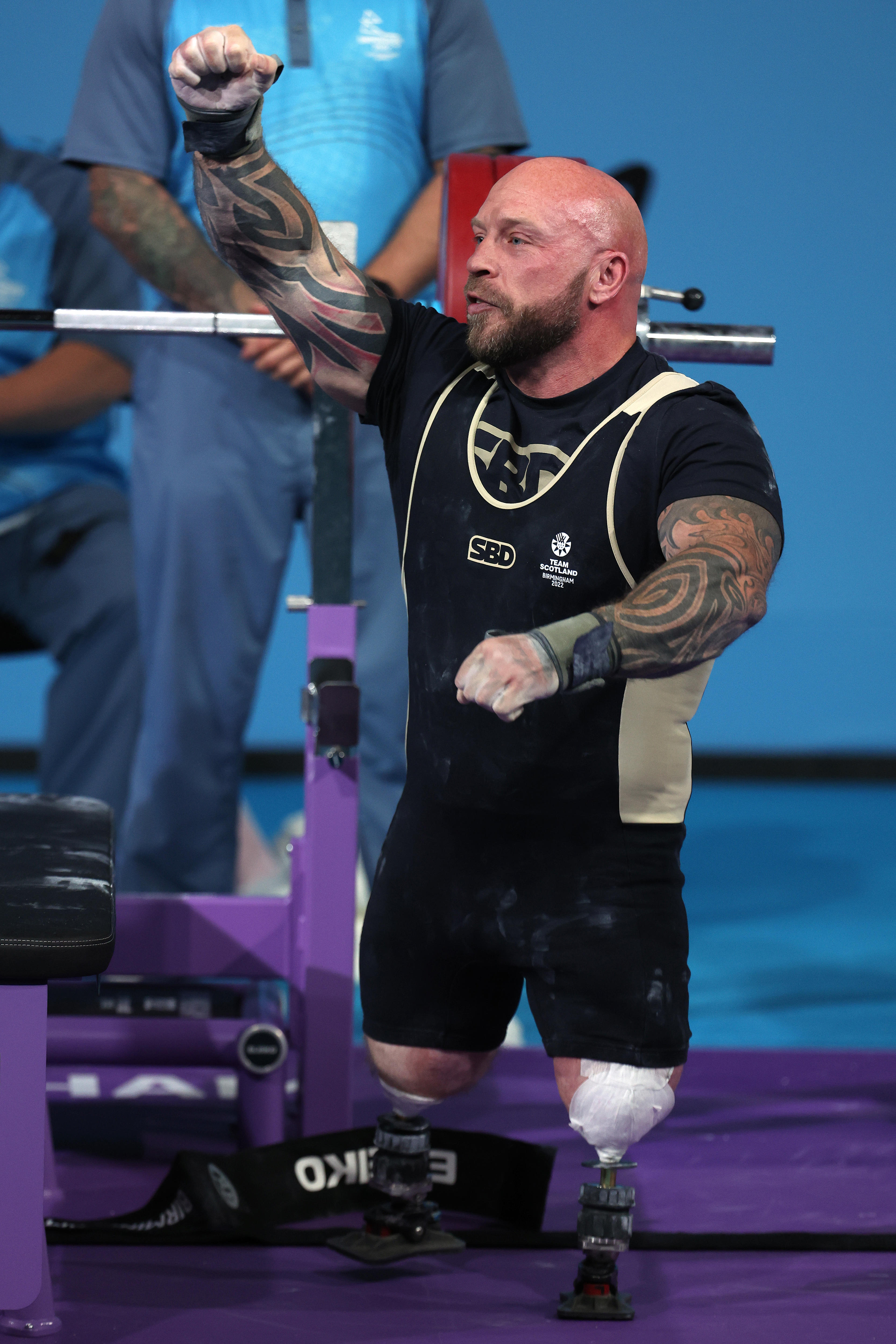 A man wearing black and white punches the air during a weightlifting competition