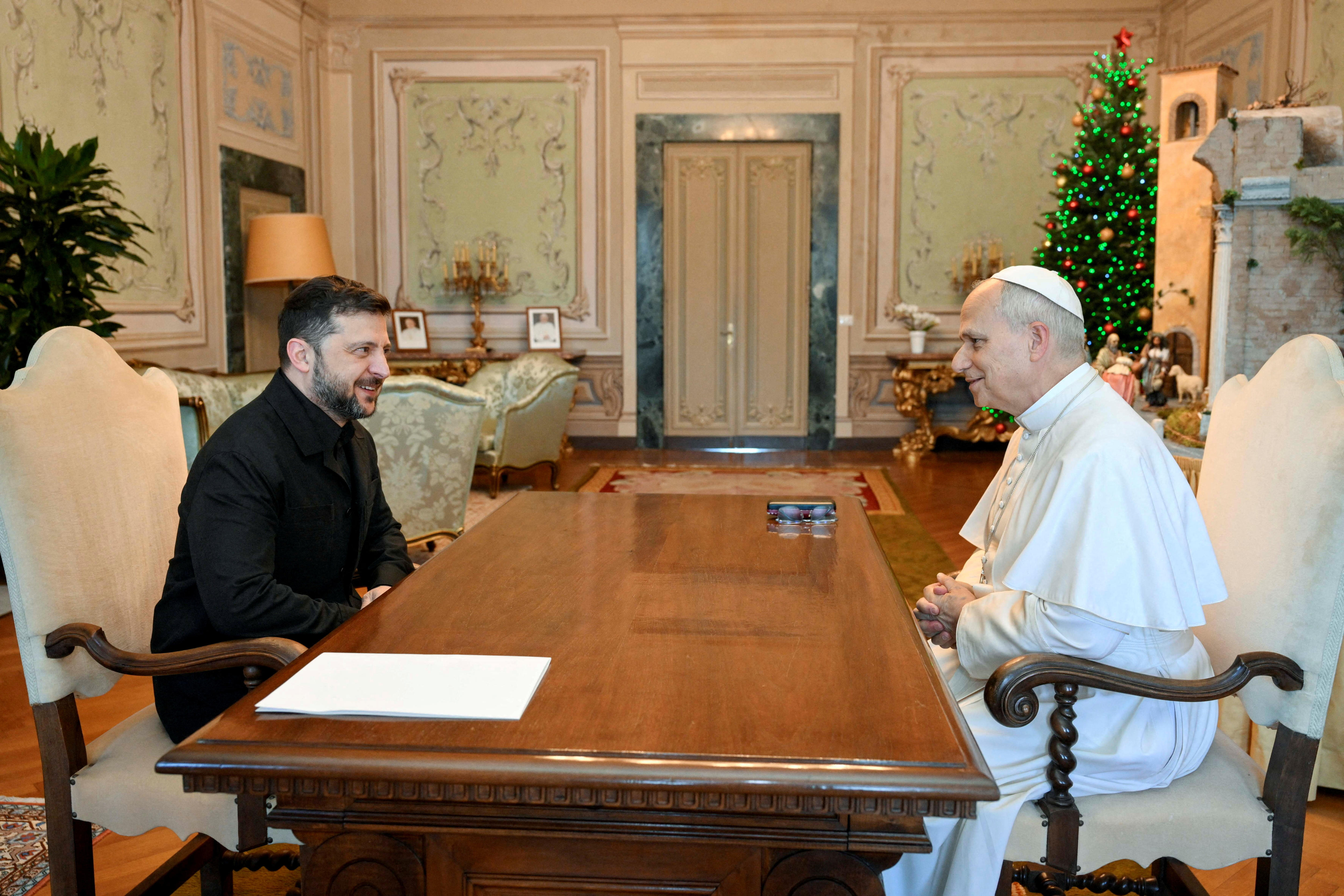 Zelenskyy sits opposite Pope Leo on a table in an old room.