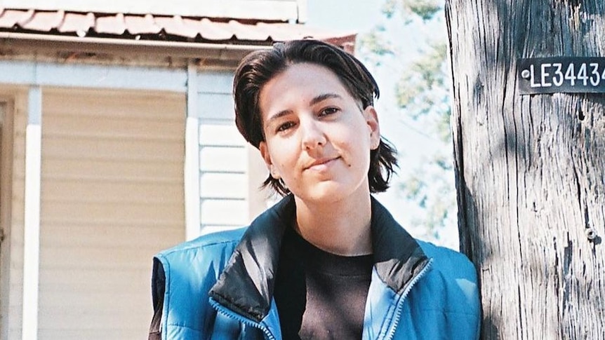 a photo of a person leaning against a street pole 