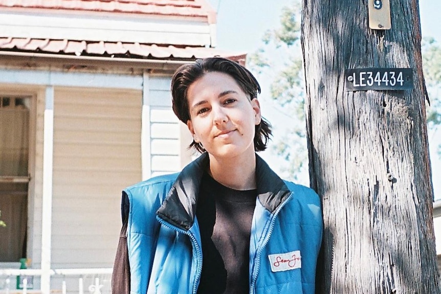 a photo of a person leaning against a street pole 