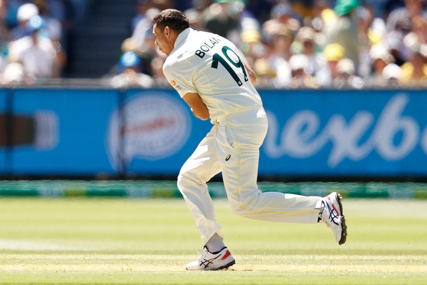 Scott Boland takes a catch at waist height while in his bowling follow through