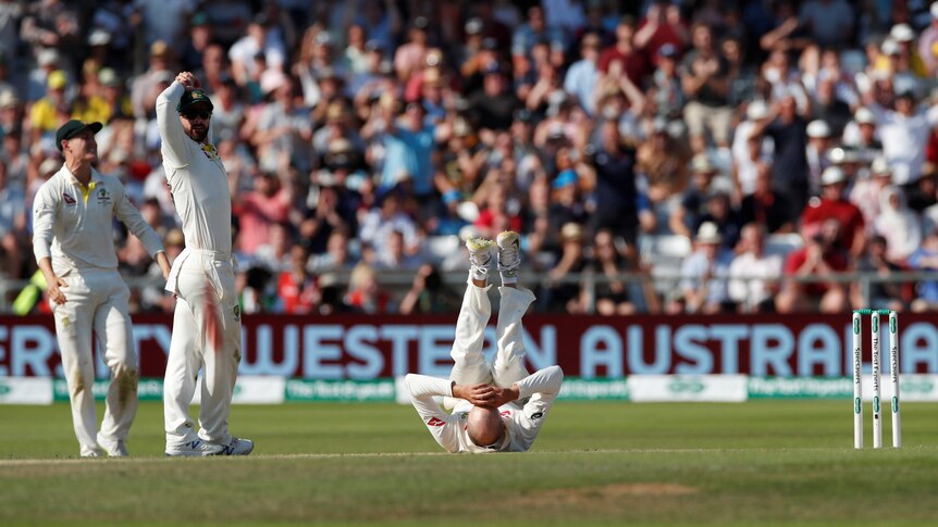 Nathan Lyon lies on his back with his legs in the air
