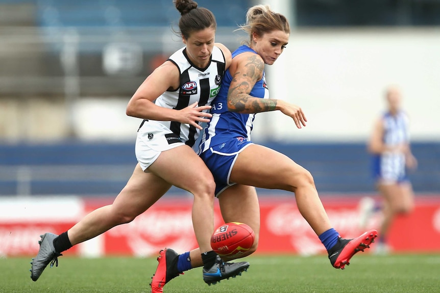 Sophie Abbatangelo runs, looking down at an AFL ball, while a Collingwood player pushes against her back with her shoulder